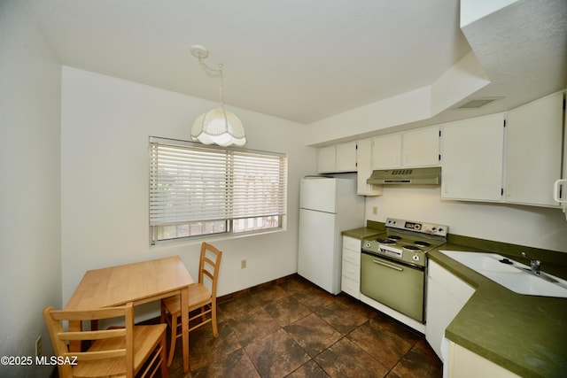 kitchen featuring under cabinet range hood, dark countertops, freestanding refrigerator, and electric range oven