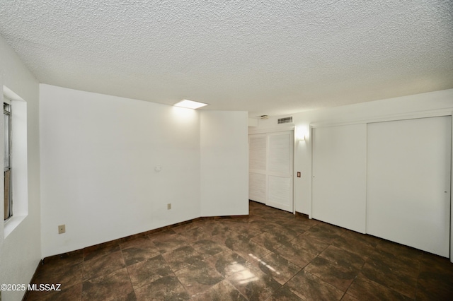 basement with visible vents, stone finish flooring, and a textured ceiling