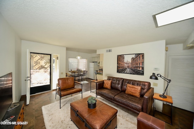 living room featuring a textured ceiling, a skylight, and visible vents