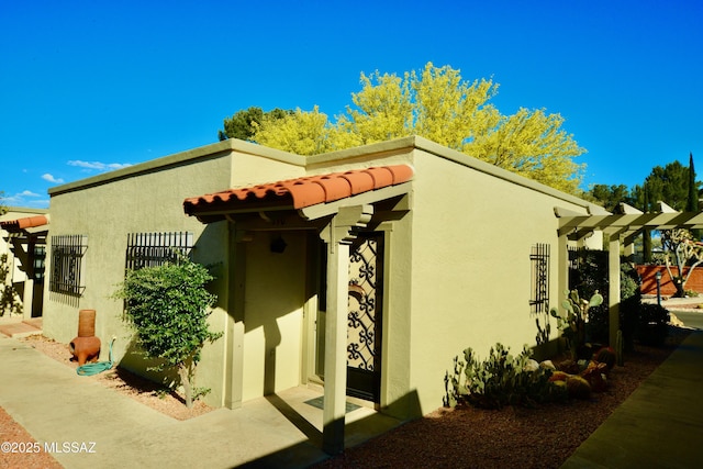view of side of property with stucco siding and a tile roof