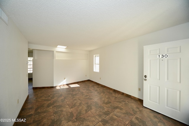 spare room with baseboards, a textured ceiling, and visible vents