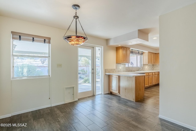 kitchen featuring backsplash, dark wood-style flooring, pendant lighting, light countertops, and baseboards