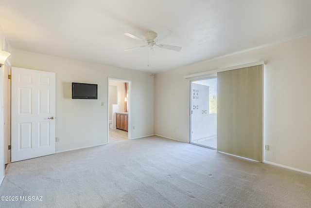 unfurnished bedroom with baseboards, a ceiling fan, ensuite bath, and light carpet