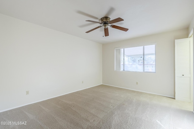 spare room with baseboards, ceiling fan, and light carpet