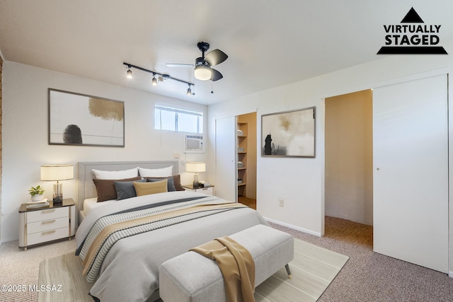 bedroom featuring track lighting, ceiling fan, light carpet, and a wall mounted air conditioner