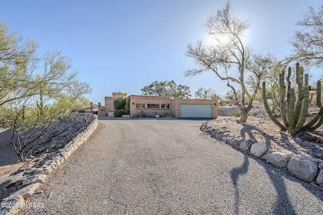 adobe home featuring brick siding, aphalt driveway, and a garage