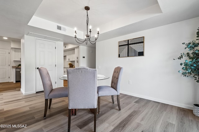 dining space featuring light wood-style floors, a tray ceiling, and a chandelier
