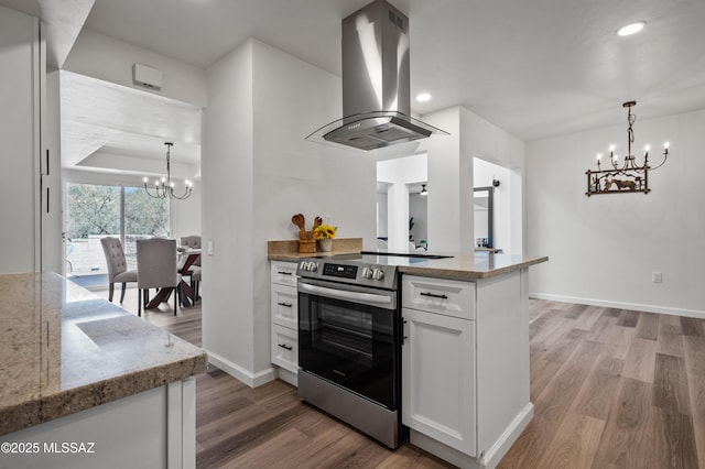 kitchen featuring stainless steel range with electric cooktop, an inviting chandelier, light wood-style floors, white cabinetry, and island range hood