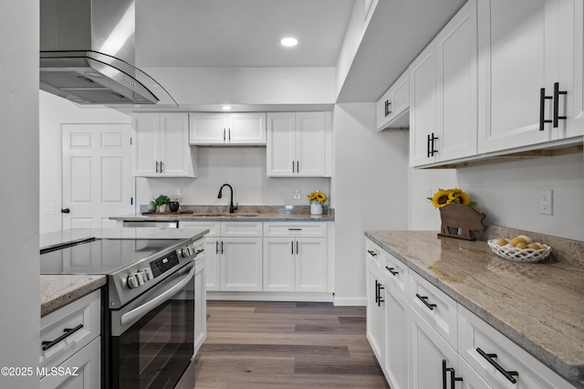 kitchen with stainless steel electric range, a sink, wall chimney exhaust hood, recessed lighting, and white cabinetry