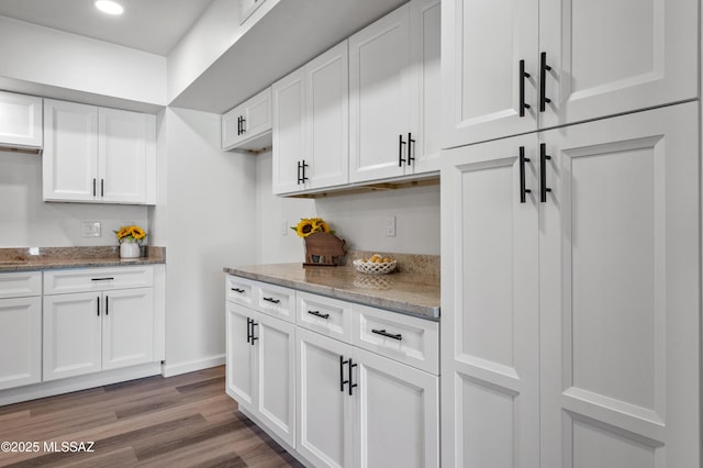 kitchen with recessed lighting, white cabinetry, wood finished floors, and light stone countertops