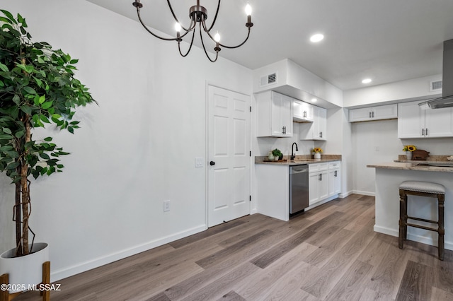 kitchen featuring white cabinets, stainless steel dishwasher, wood finished floors, and visible vents