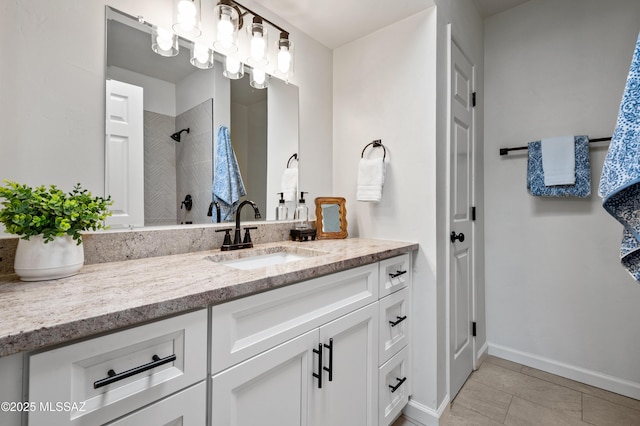 bathroom with vanity, baseboards, tile patterned floors, and tiled shower