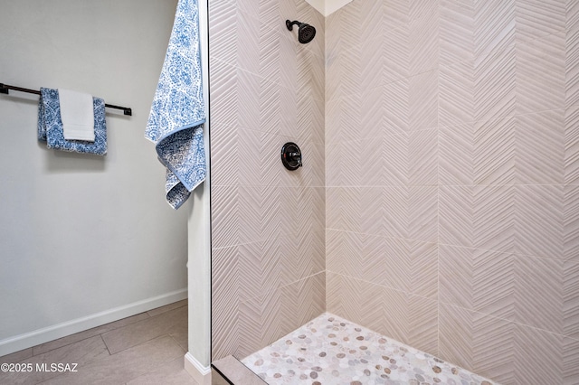 bathroom featuring baseboards, a tile shower, and tile patterned flooring
