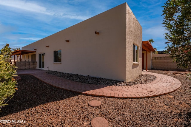 view of side of property featuring fence, stucco siding, and a patio area