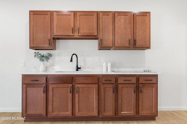 kitchen with a sink, light countertops, baseboards, and light wood-style flooring