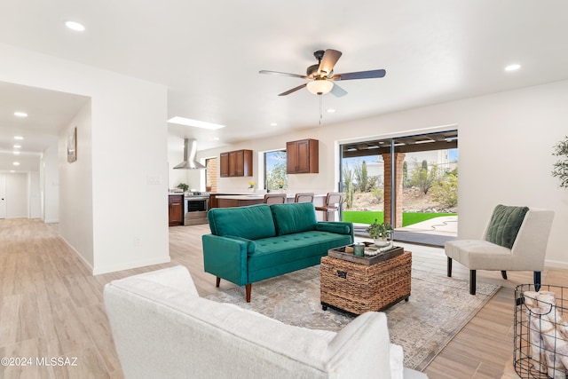 living area featuring baseboards, a ceiling fan, light wood finished floors, and recessed lighting