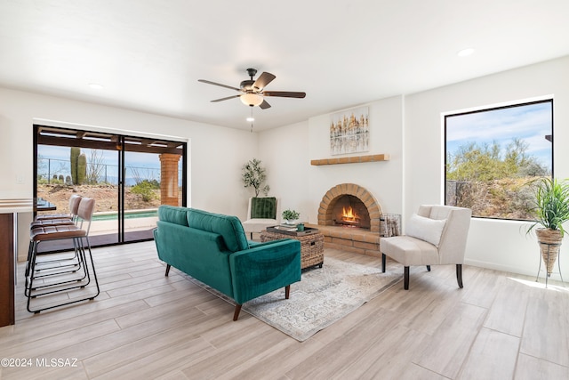 living room with recessed lighting, a ceiling fan, a brick fireplace, and light wood finished floors
