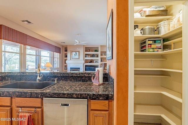 kitchen featuring ceiling fan, visible vents, stainless steel dishwasher, a sink, and tile counters