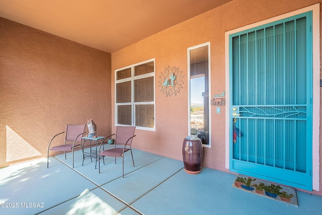 view of exterior entry featuring a patio area and stucco siding