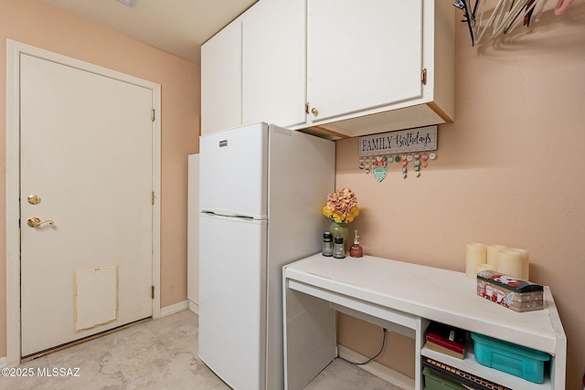 kitchen with freestanding refrigerator, white cabinetry, and light countertops