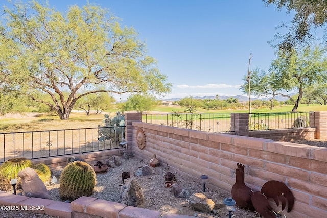 view of yard with view of golf course, a mountain view, and fence