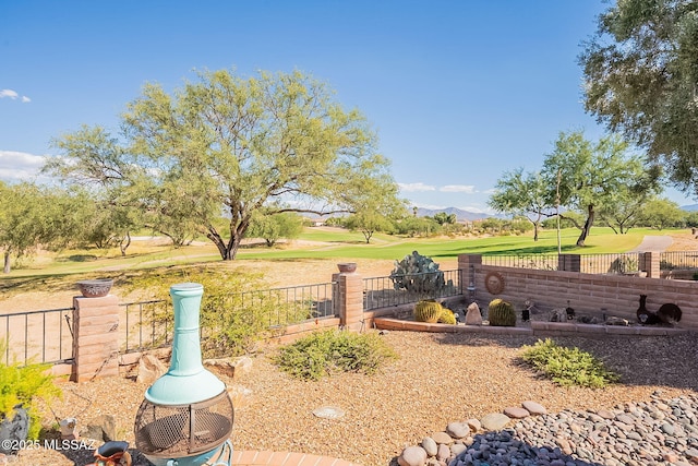 view of yard featuring a mountain view, fence, and golf course view