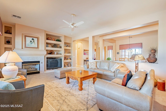 living area with ceiling fan, visible vents, built in features, and a fireplace