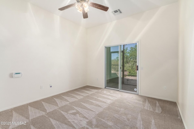 carpeted spare room featuring ceiling fan, visible vents, and baseboards