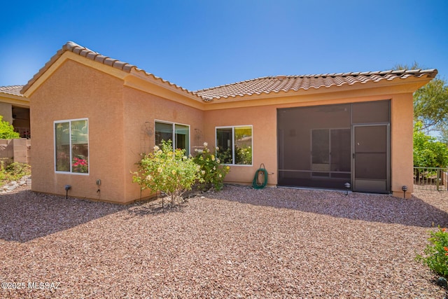 back of property featuring stucco siding, a tile roof, and fence