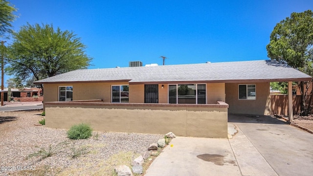 view of front facade with fence, an attached carport, concrete driveway, and roof with shingles
