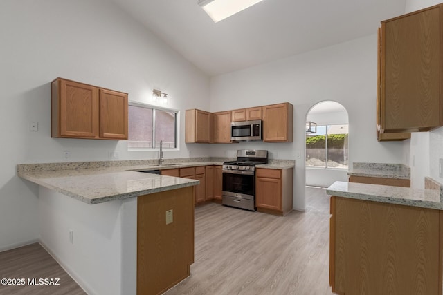 8073 S High Canyon Dr, Tucson, AZ 85747 - kitchen with stainless steel appliances, a peninsula, a sink, light stone countertops, and light wood-style flooring