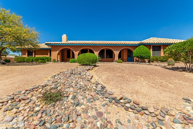 mediterranean / spanish house with a tiled roof, a porch, and a chimney