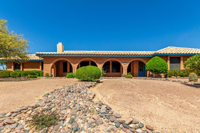mediterranean / spanish-style home with a tile roof, a chimney, and a porch