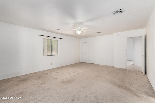 empty room with light colored carpet, a ceiling fan, and visible vents