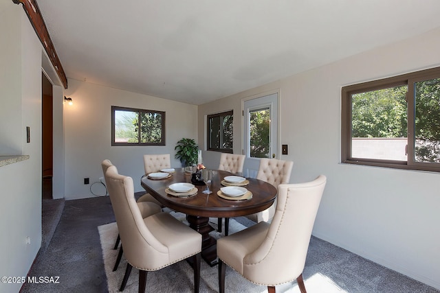 dining room with dark colored carpet and plenty of natural light