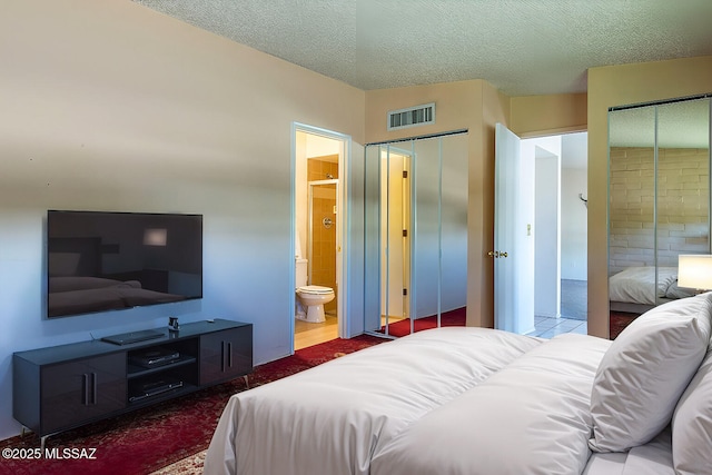 bedroom with visible vents, carpet, a textured ceiling, and ensuite bath