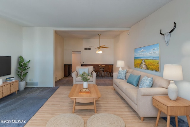 living area featuring a ceiling fan, visible vents, and wood finished floors