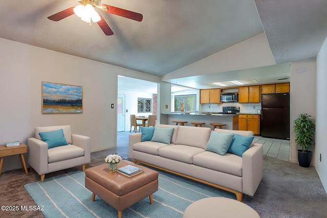 living area with ceiling fan, lofted ceiling, and light colored carpet