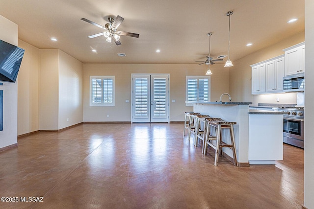 kitchen with plenty of natural light, a center island with sink, ceiling fan, and stainless steel appliances
