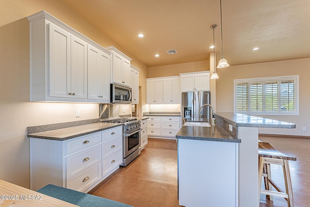 kitchen with white cabinets, dark countertops, a breakfast bar, a sink, and stainless steel appliances