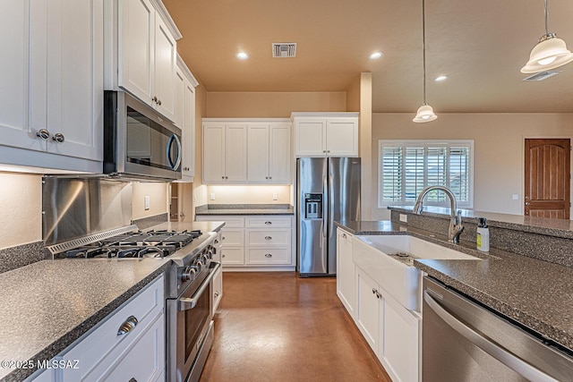 kitchen featuring white cabinets, concrete flooring, hanging light fixtures, a sink, and stainless steel appliances