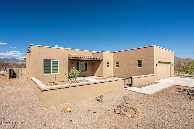 adobe home featuring fence, stucco siding, a gate, driveway, and a tile roof