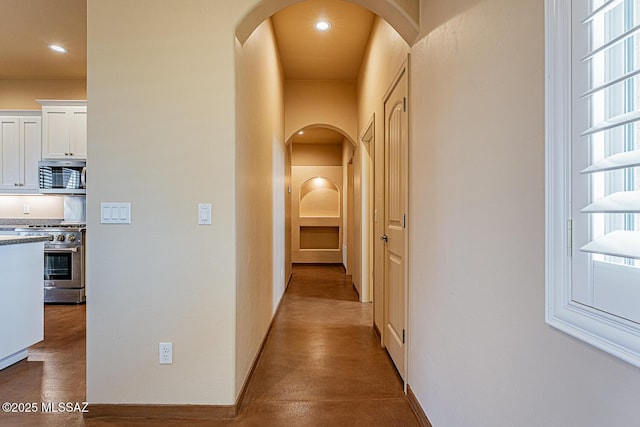 hall with recessed lighting, arched walkways, and baseboards