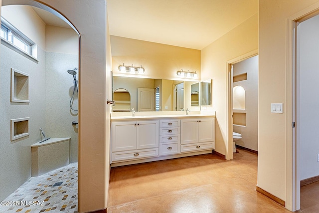 full bathroom featuring walk in shower, a sink, double vanity, toilet, and baseboards