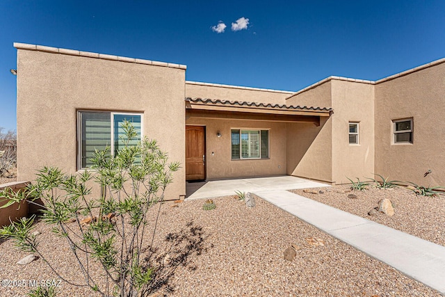 adobe home featuring a patio, stucco siding, and a tiled roof