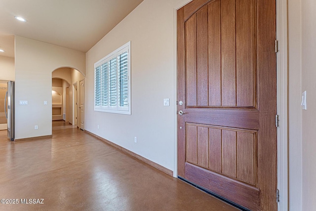 interior space featuring baseboards, arched walkways, concrete floors, and recessed lighting