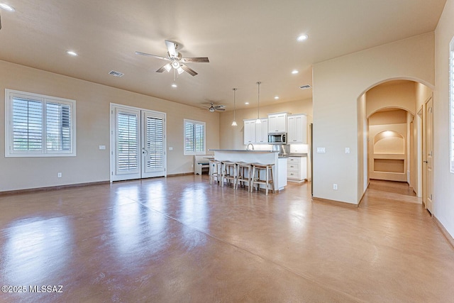living room with visible vents, recessed lighting, arched walkways, finished concrete floors, and a ceiling fan