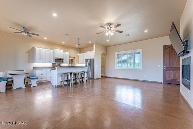 living room featuring a ceiling fan, visible vents, recessed lighting, and finished concrete floors