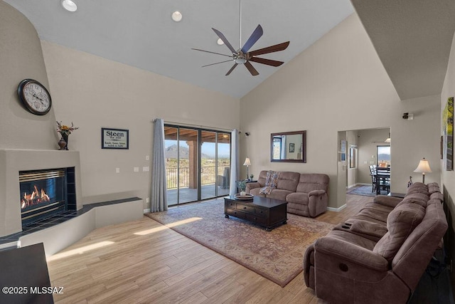 14171 N Gibson Trl, Tucson, AZ 85755 - living area with high vaulted ceiling, wood finished floors, a ceiling fan, a tiled fireplace, and baseboards