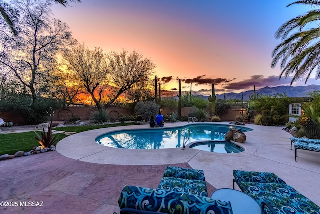 pool at dusk featuring a fenced in pool, a patio, an in ground hot tub, and a fenced backyard
